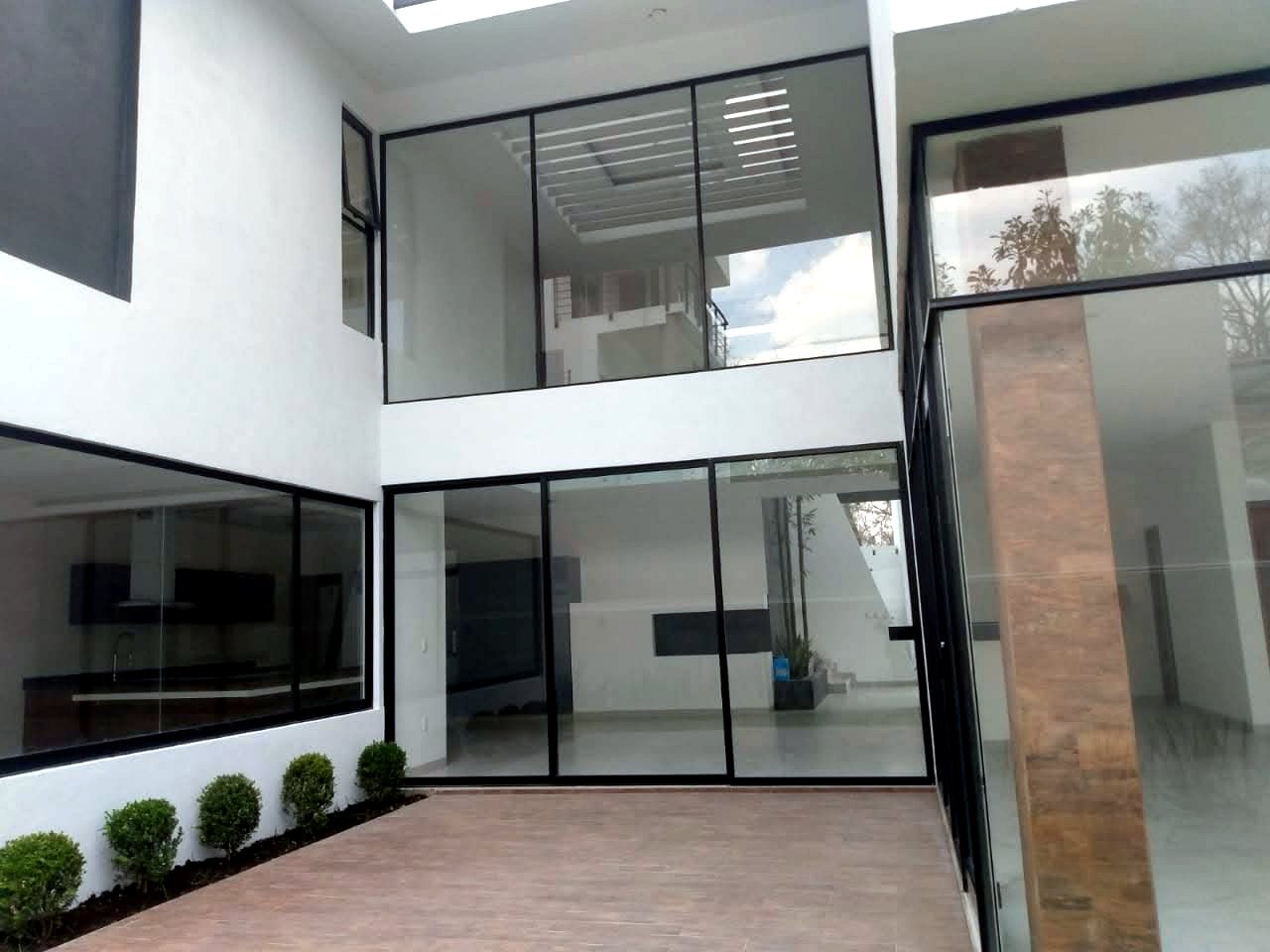 Patio interior de doble altura con muros de cristal, Residencia CDMX
